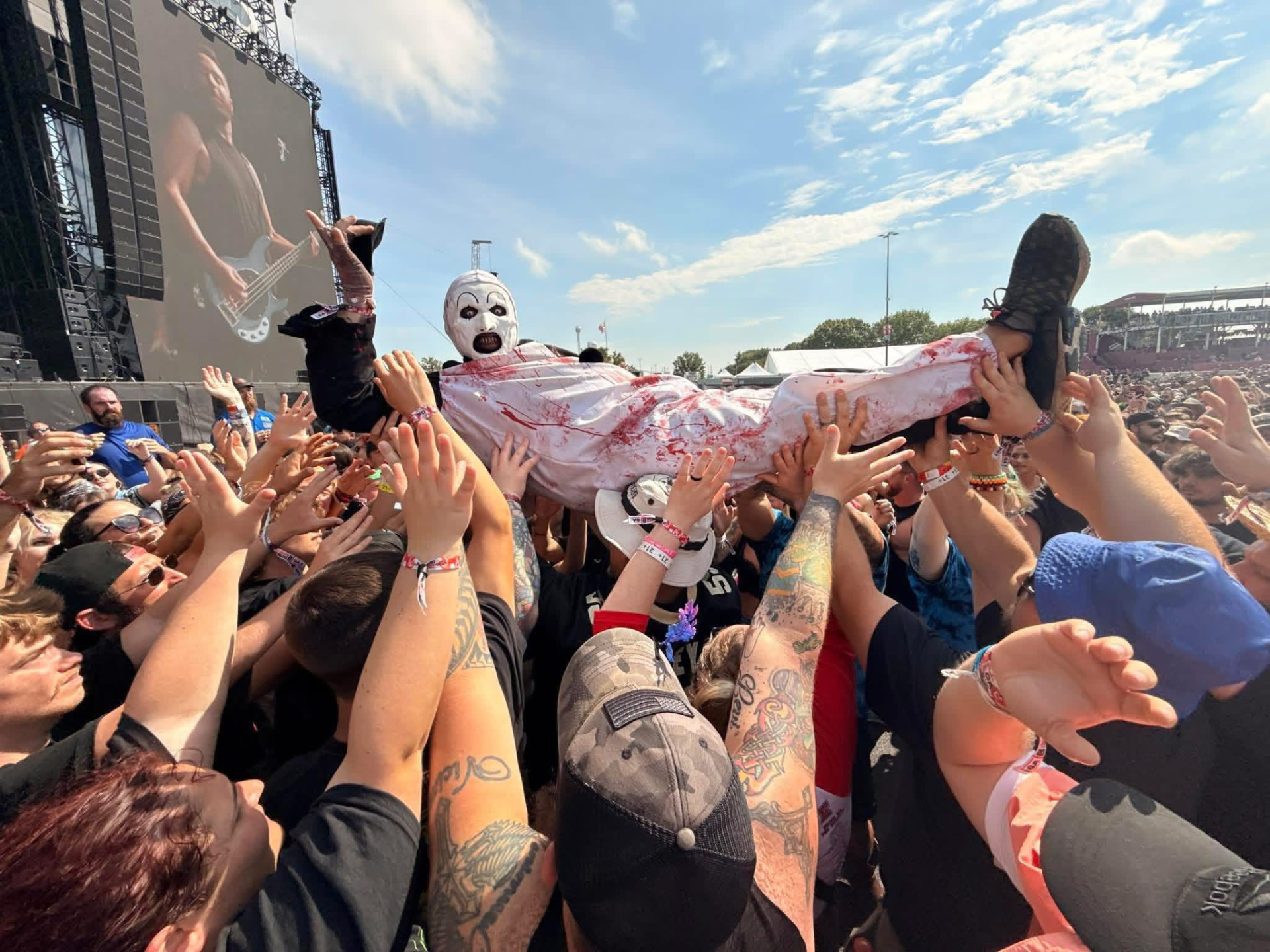 Art the Clown crowd surfing in a blood-soaked gown over a Rockville festival crowd